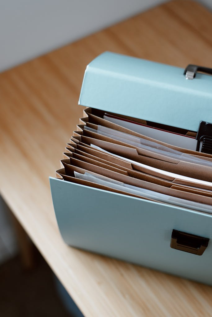 From above of opened modern briefcase with prepared papers placed on timber table in soft focus